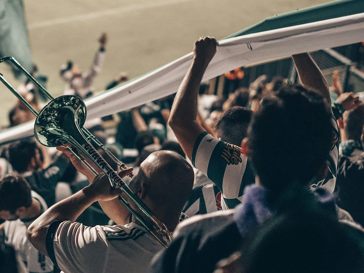 Fans cheering in the stands with a trombone and a banner