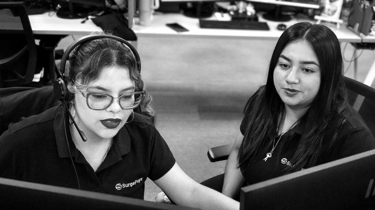 Two SurgePays support team members working together at a screen